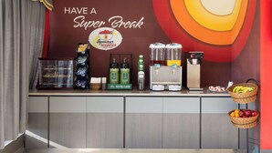 A breakfast bar with a sign reading "Have a Super Break," a coffee machine, juice dispensers, and baskets of fruits. - Super 8 by Wyndham Hazleton (Hazleton)