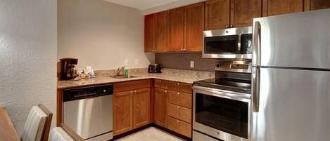 A modern kitchen with stainless steel appliances, wooden cabinets, and a granite countertop.