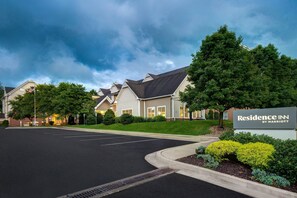A hotel entrance with a sign reading "Residence Inn by Marriott" and a parking lot in front.