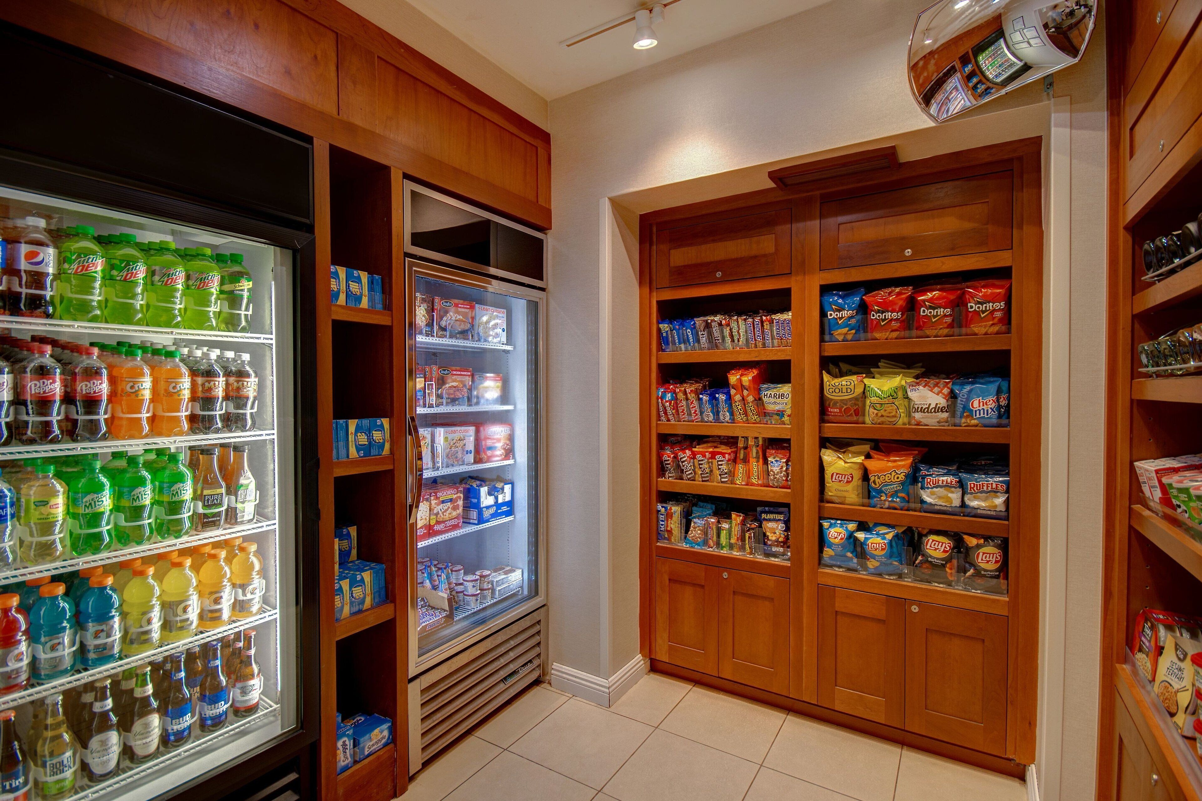 A snack and beverage refrigerator stocked with various drinks and snacks, including sodas and chips.