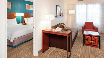 Une chambre d’hôtel comprenant un lit, un bureau avec un téléphone, une chaise et une lampe.