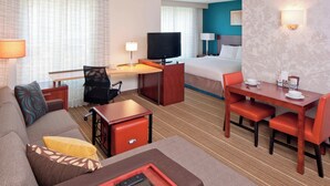 Une chambre d’hôtel comprenant un lit, un bureau avec une télévision, un canapé et un coin repas.