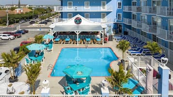 A hotel with a pool area, outdoor seating, and a view of the ocean.