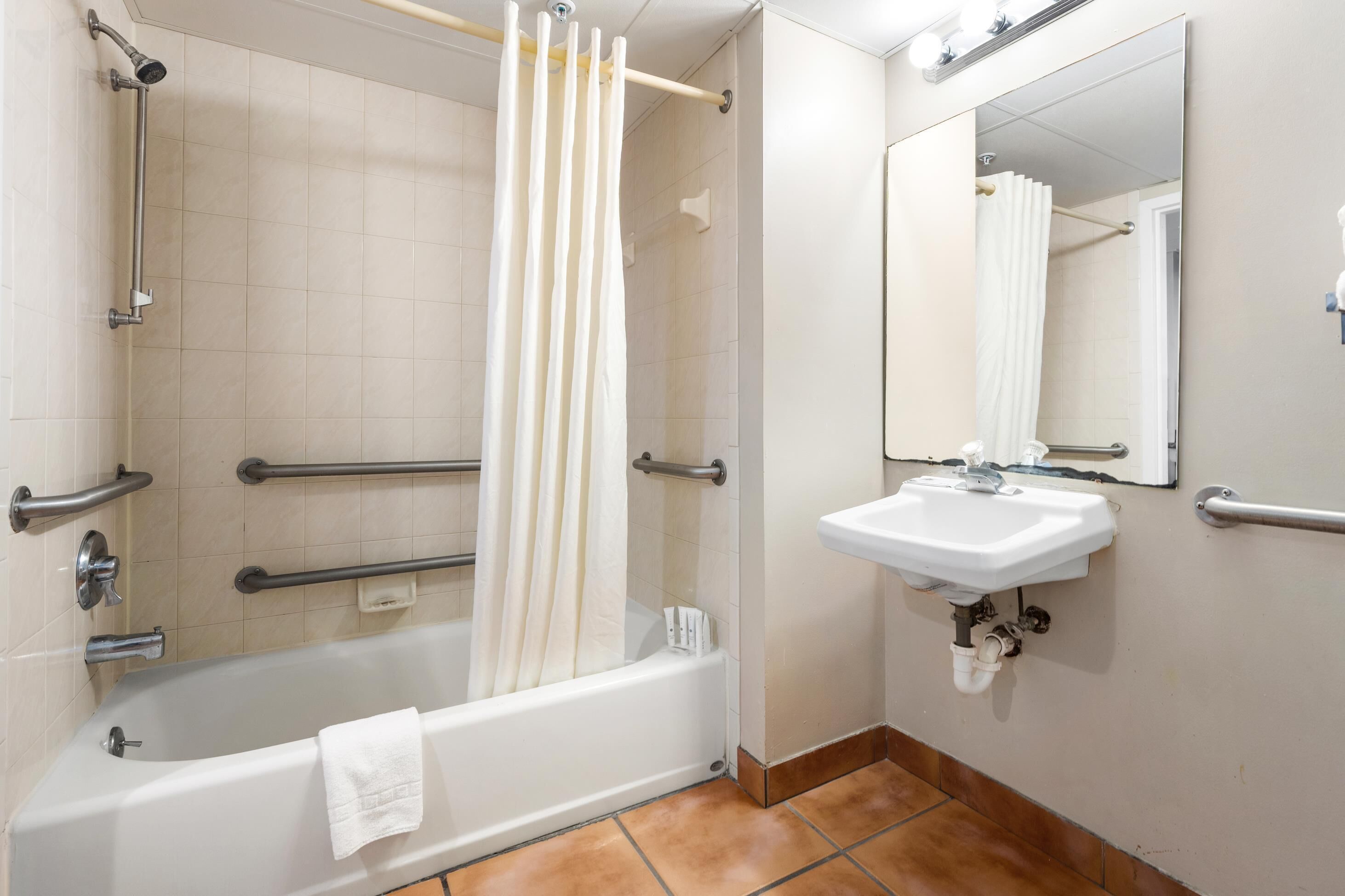 A bathroom with a bathtub, a shower, a sink, and a mirror.