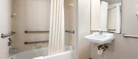 A bathroom with a bathtub, a shower, a sink, and a mirror.