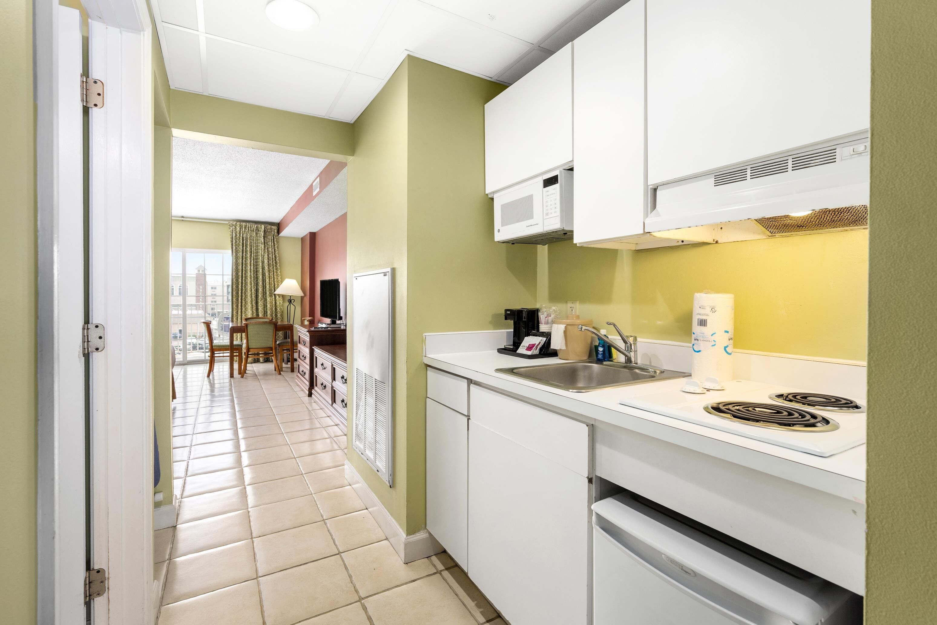 A kitchen with white cabinets, a microwave, a sink, and a stove.