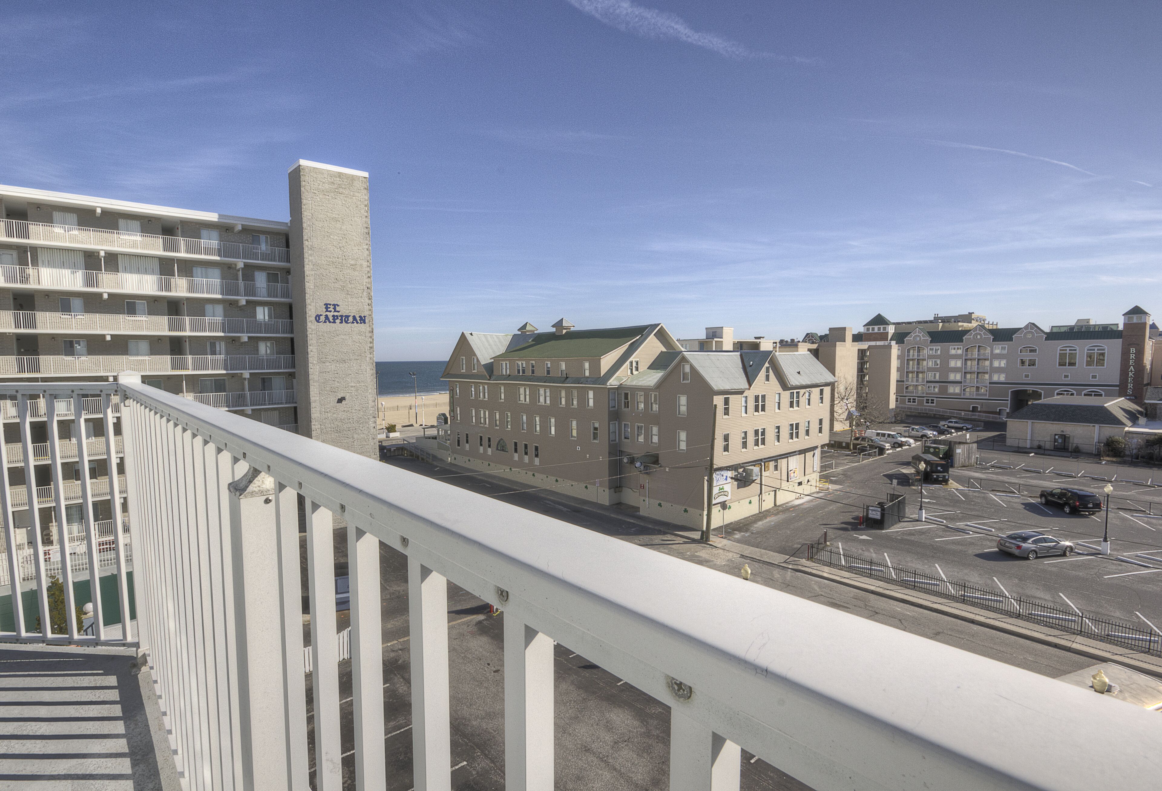 A hotel with multiple floors, a prominent tower, and a parking lot with cars.