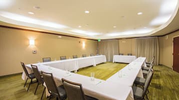 Un salón de conferencias con una mesa larga, sillas y piso alfombrado.