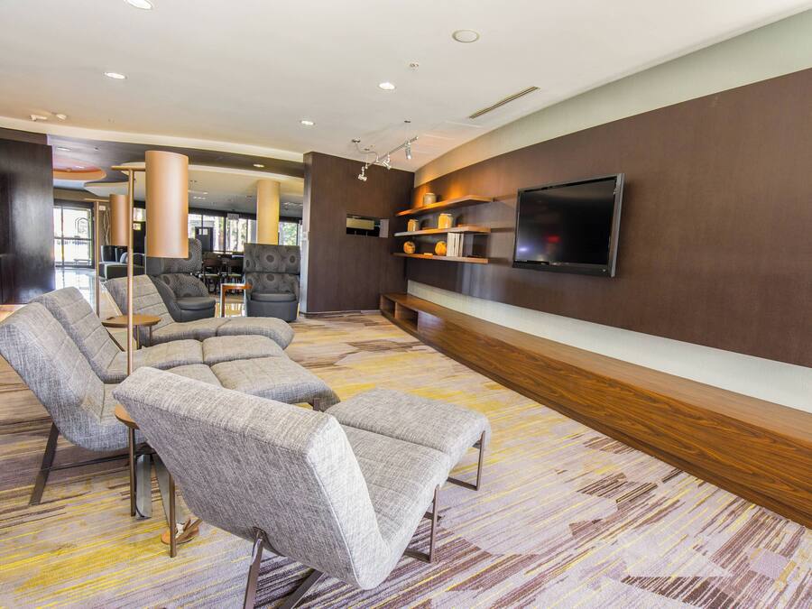 A modern lounge area with a flat-screen TV mounted on the wall, a sofa, and a coffee table.