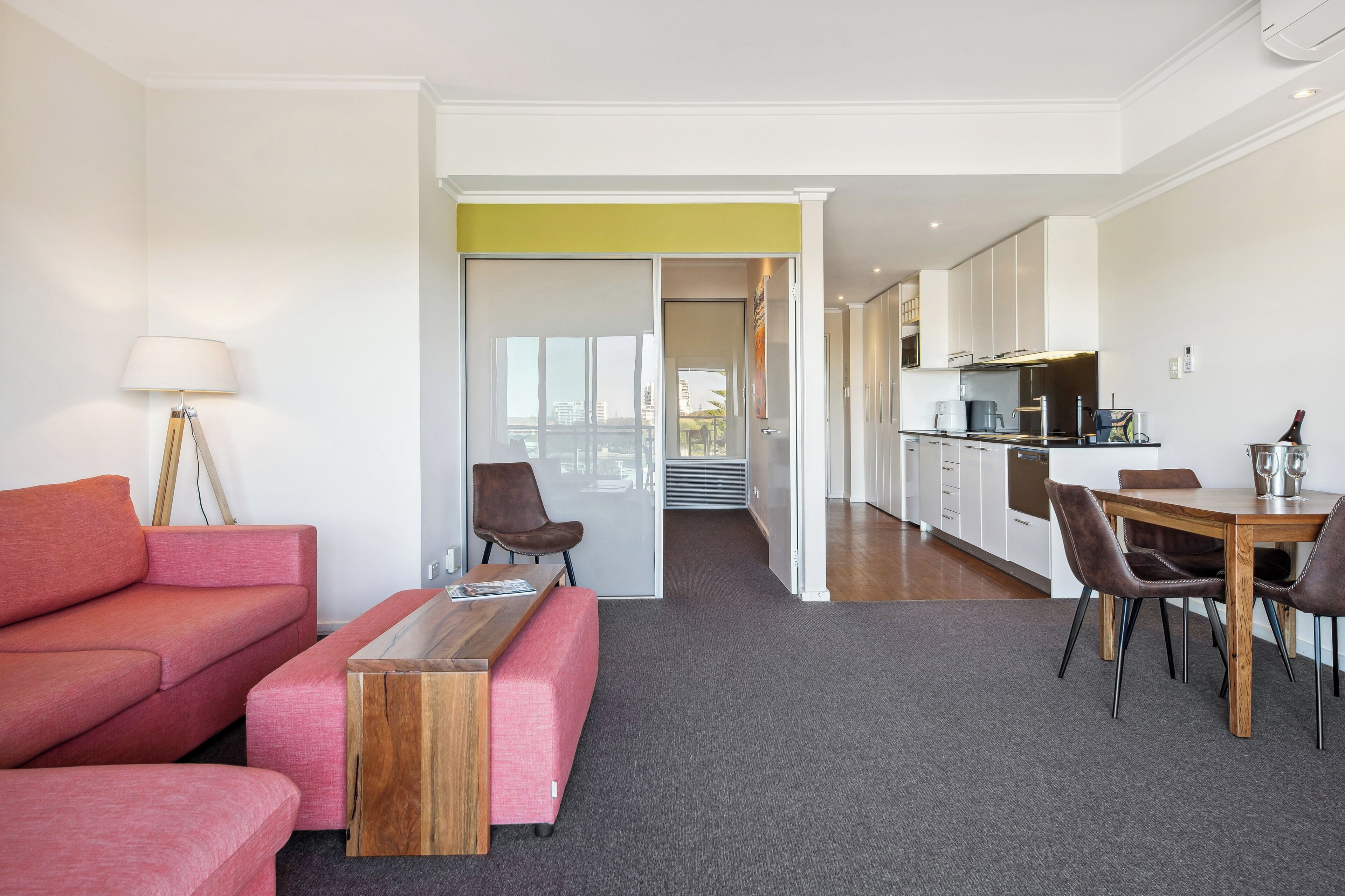 A modern living room with a sofa, a coffee table, and a dining area with a table and chairs.