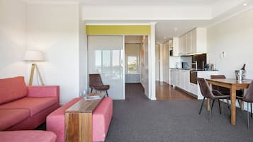 A modern living room with a sofa, a coffee table, and a dining area with a table and chairs.