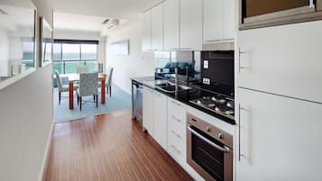 Una cocina moderna con armarios blancos, electrodomésticos de acero inoxidable y un comedor con sillas estampadas.