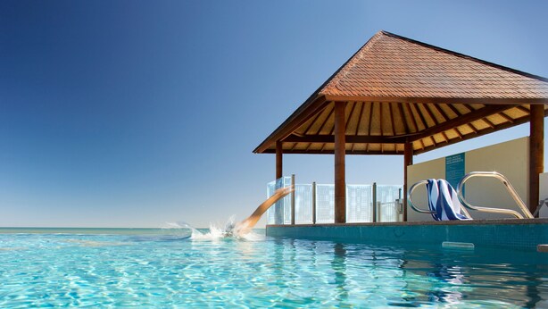 Una piscina azul cristalina con una estructura de madera y un tobogán.