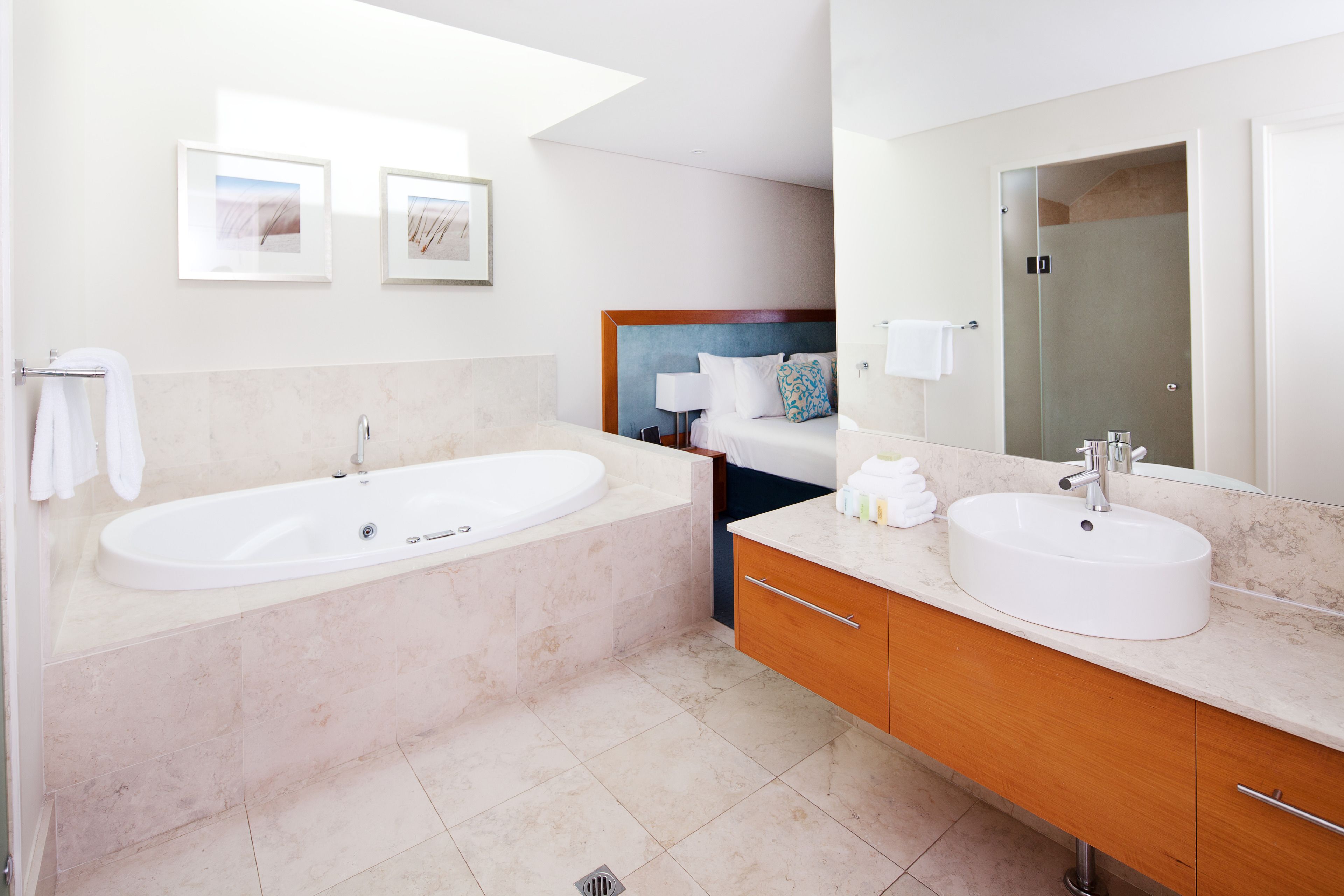 A modern bathroom with a large bathtub, a double sink vanity, and a large mirror.