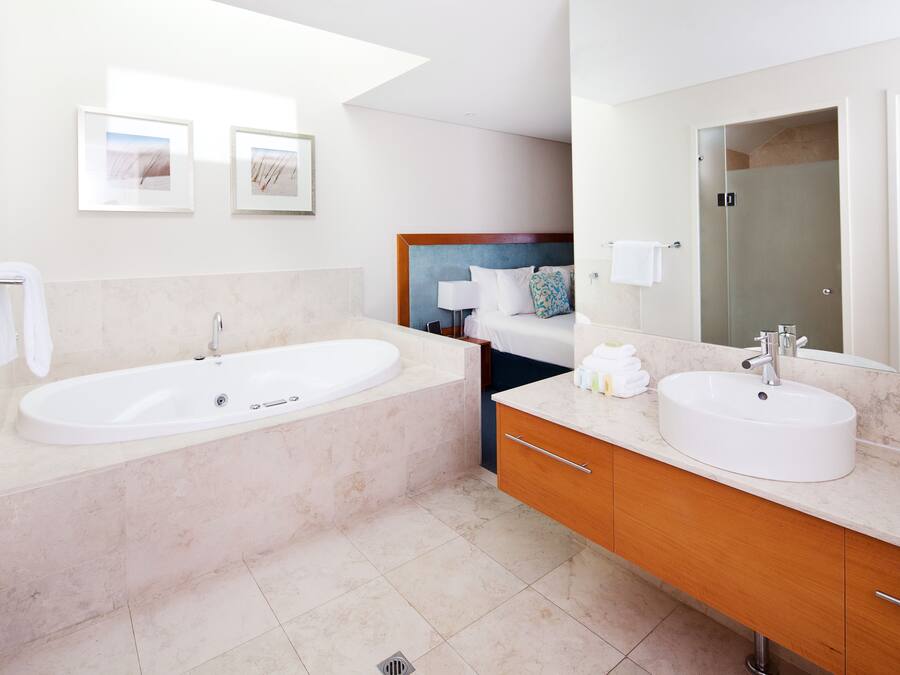 Un baño moderno con una bañera grande, un tocador doble y un espejo amplio.