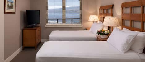 A hotel room with two beds, a TV, a window with a view, and a lamp.