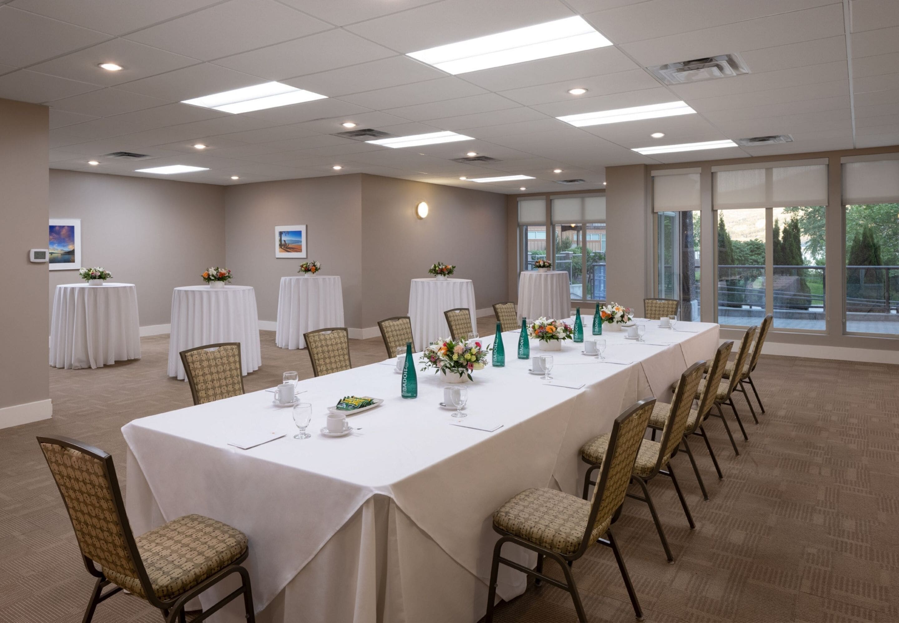 A conference room with a long table, chairs, and floral centerpieces.