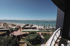 A resort with a beach view, outdoor seating, and palm trees.