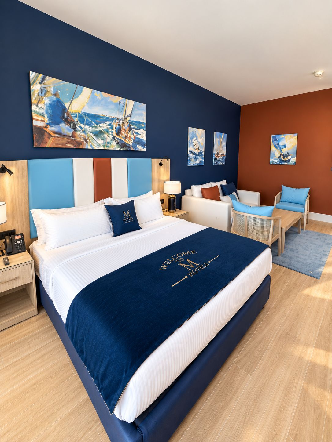 A hotel room with a large bed, a desk, a chair, and artwork on the walls.