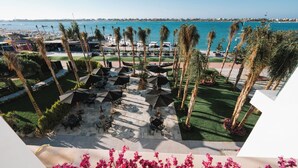 A rooftop terrace with outdoor seating, palm trees, and a view of the sea. - M Hotels at Porto Marina (El Alamein)