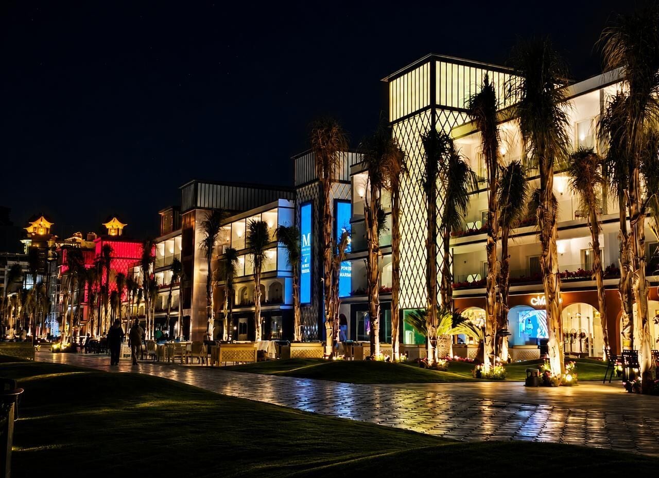 A hotel with multiple floors, palm trees, and illuminated signage.