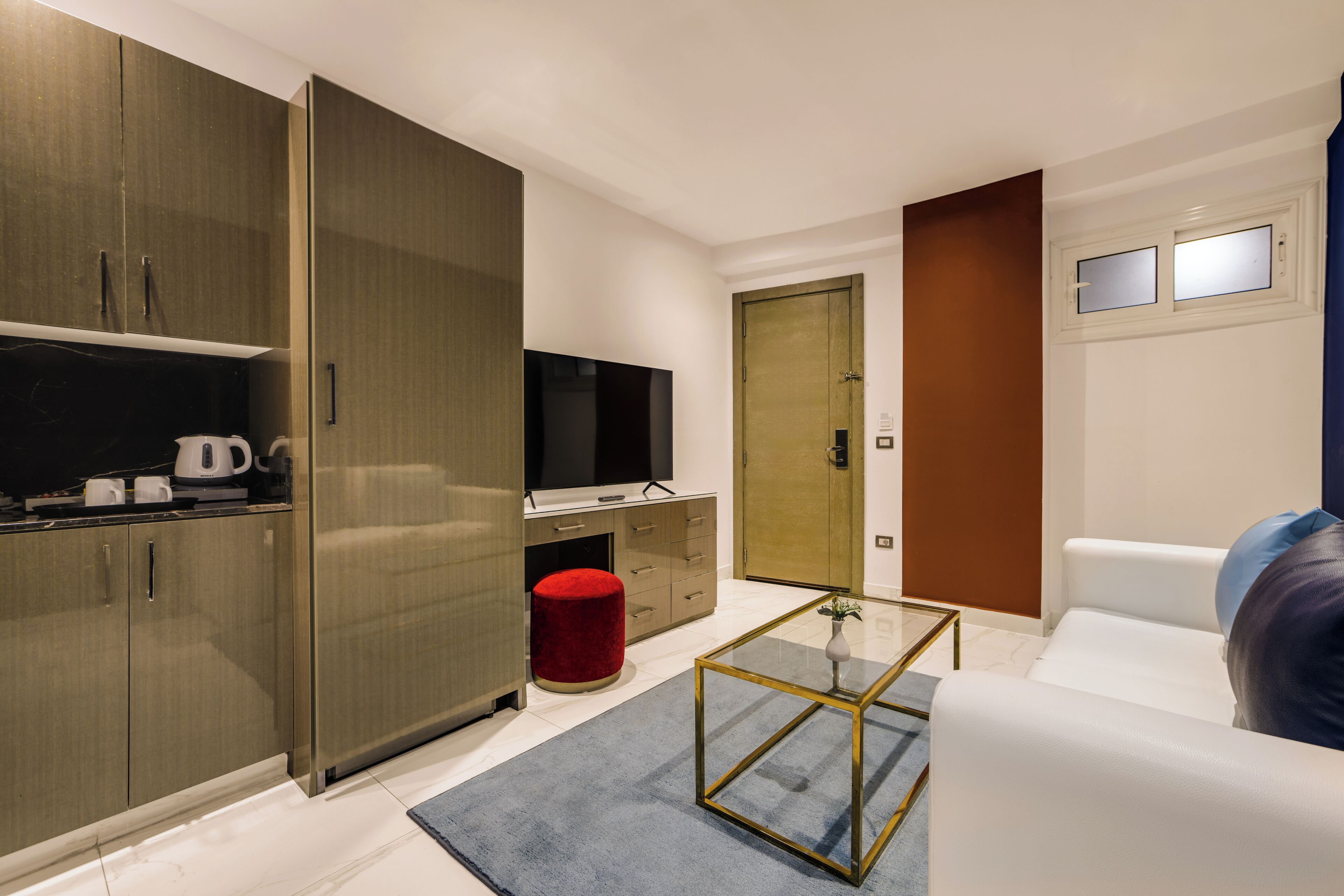 A modern room with a TV, wardrobe, sofa, and a glass coffee table.