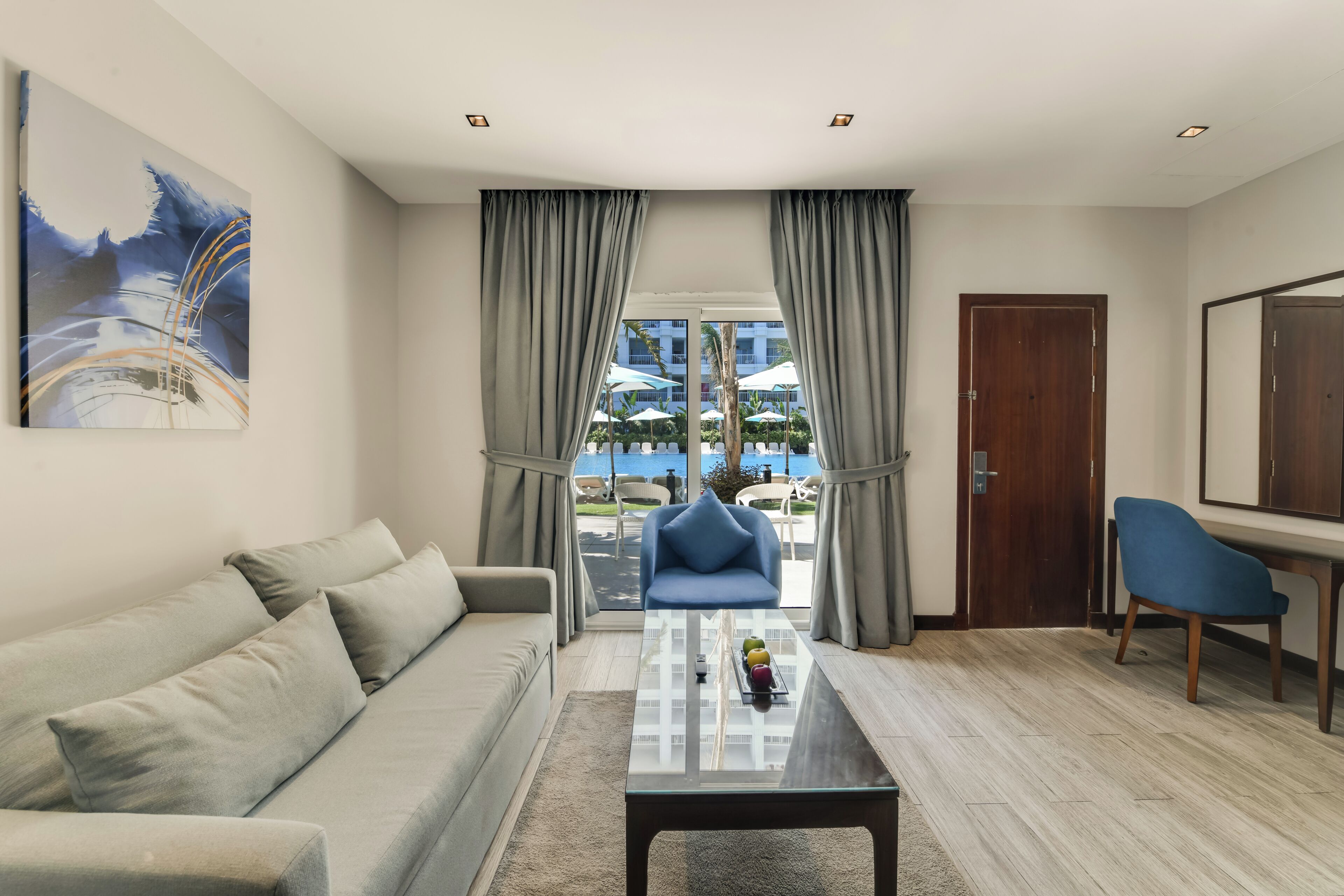 A modern living room with a sofa, a coffee table, and a view of an outdoor pool area.