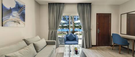 A modern living room with a sofa, a coffee table, and a view of an outdoor pool area.