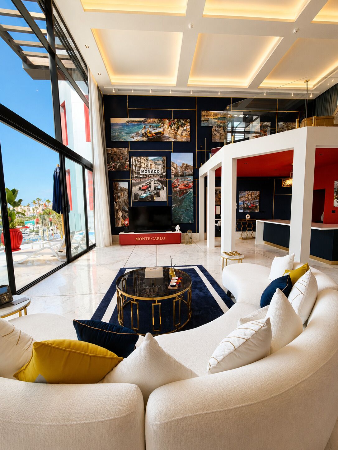 A modern living room with a white sofa, a round coffee table, and a large window overlooking a pool area.