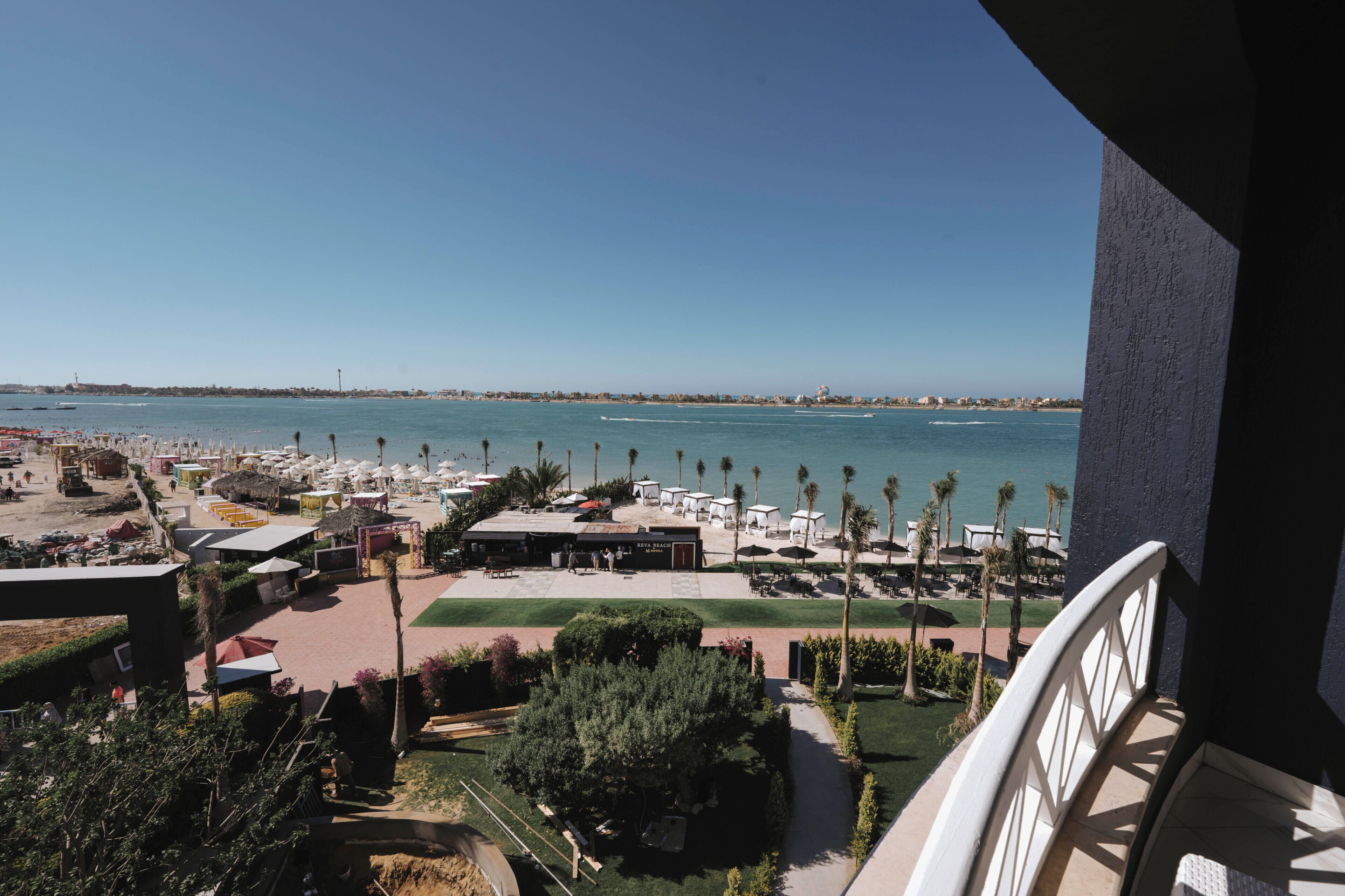A resort with a beach view, outdoor seating, and palm trees.
