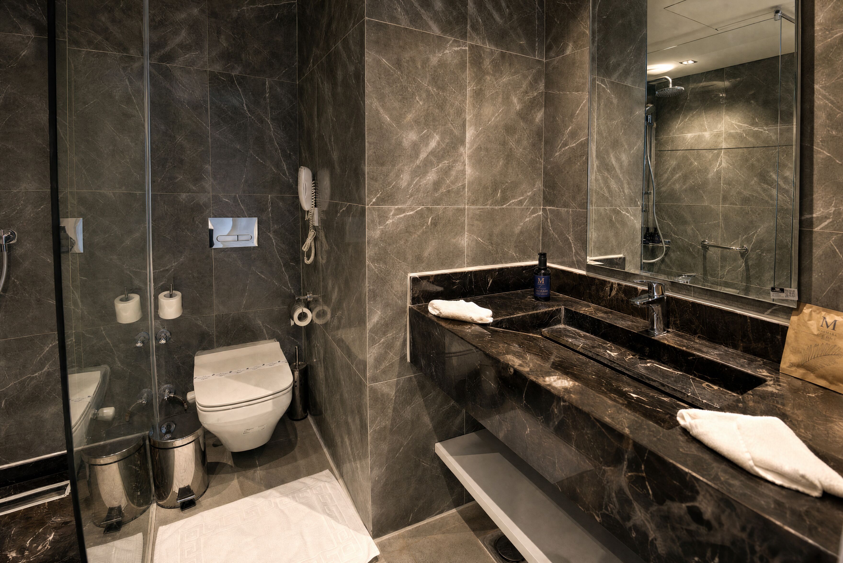 Une salle de bain moderne avec une douche à parois de verre, des toilettes, un bidet et un meuble-lavabo avec un miroir.