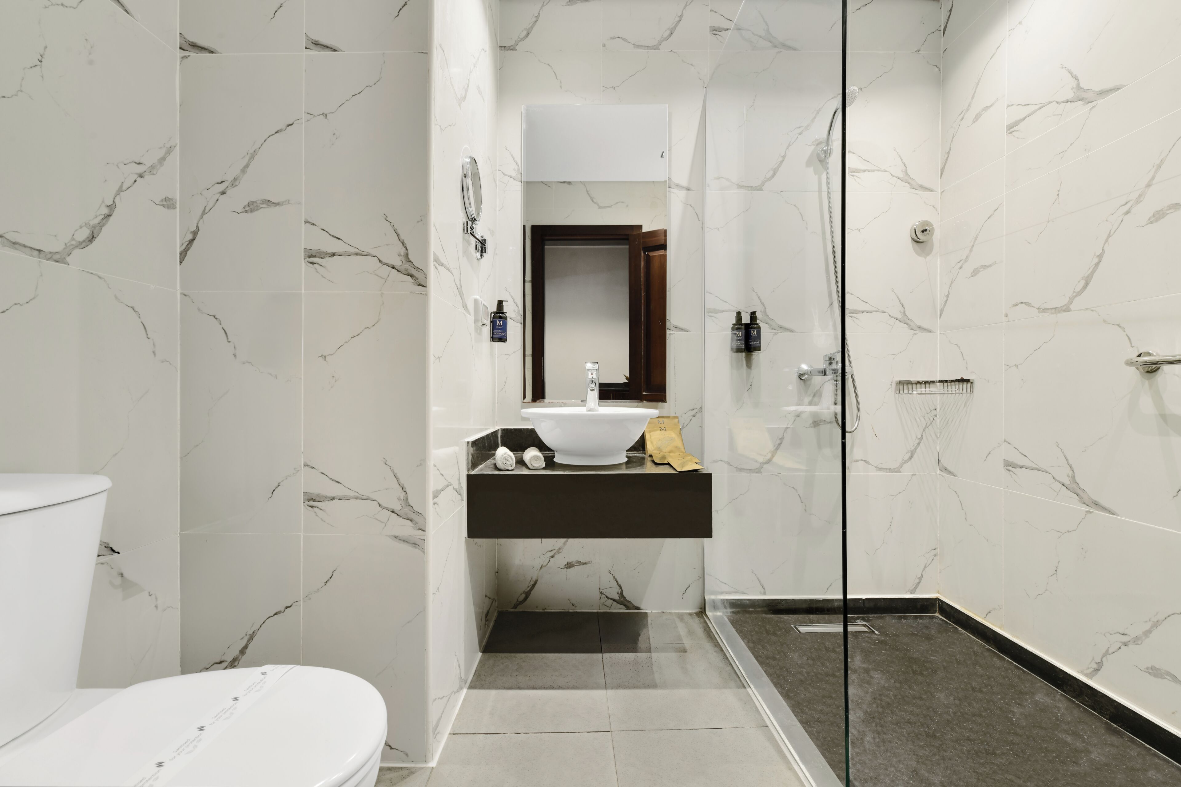 Et moderne badeværelse med toilet, vask og bruseområde.