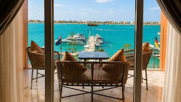 Una habitación con un ventanal grande que da a un puerto deportivo con barcos y un mar azul y despejado.