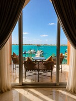 Una habitación con un ventanal grande que da a un puerto deportivo con barcos y un mar azul y despejado.
