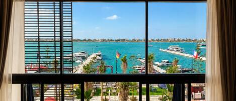 A room with a large window overlooking a marina with boats and a clear blue sky.