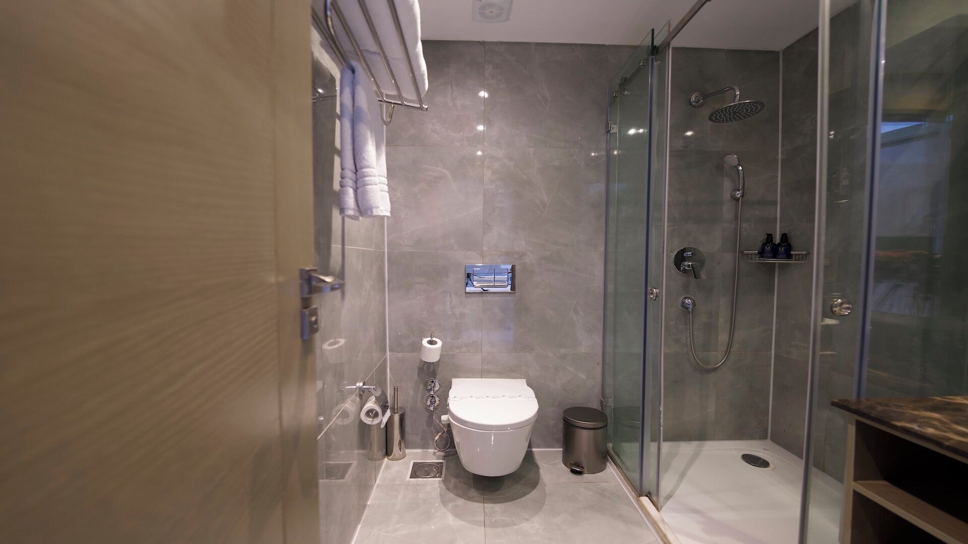 A modern bathroom with a glass-enclosed shower, a toilet, and a bidet.