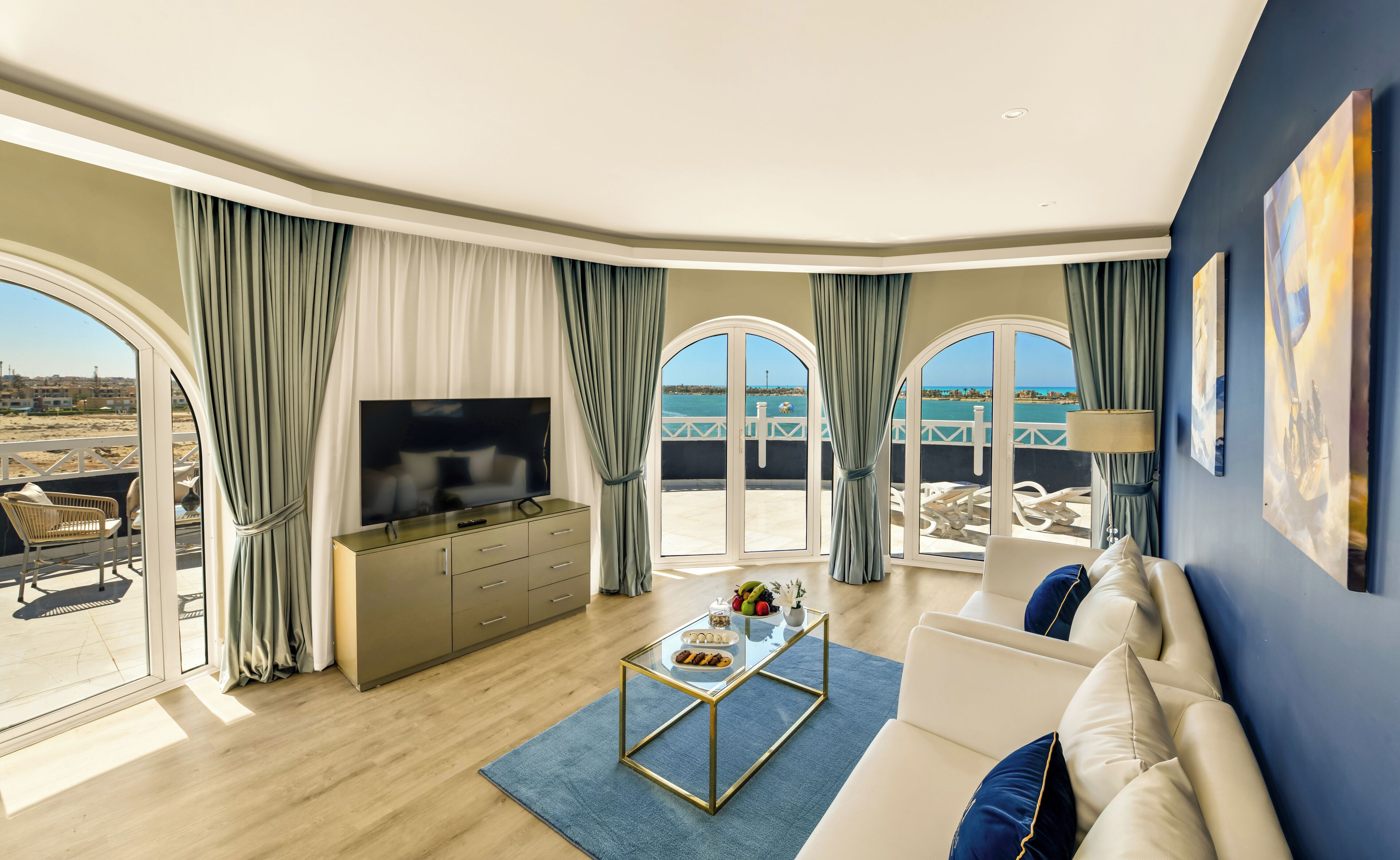 Una sala de estar moderna con televisor, zona de estar y vistas al mar.