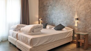 A bedroom with a large bed, two bedside lamps, and a textured wall. - Due Ragni (Villorba)
