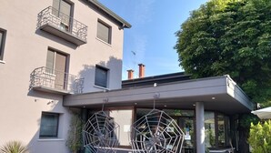 A modern building with a covered entrance, potted plants, and a clear sky. - Due Ragni (Villorba)