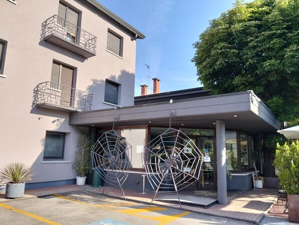 A modern building with a covered entrance, potted plants, and a clear sky.