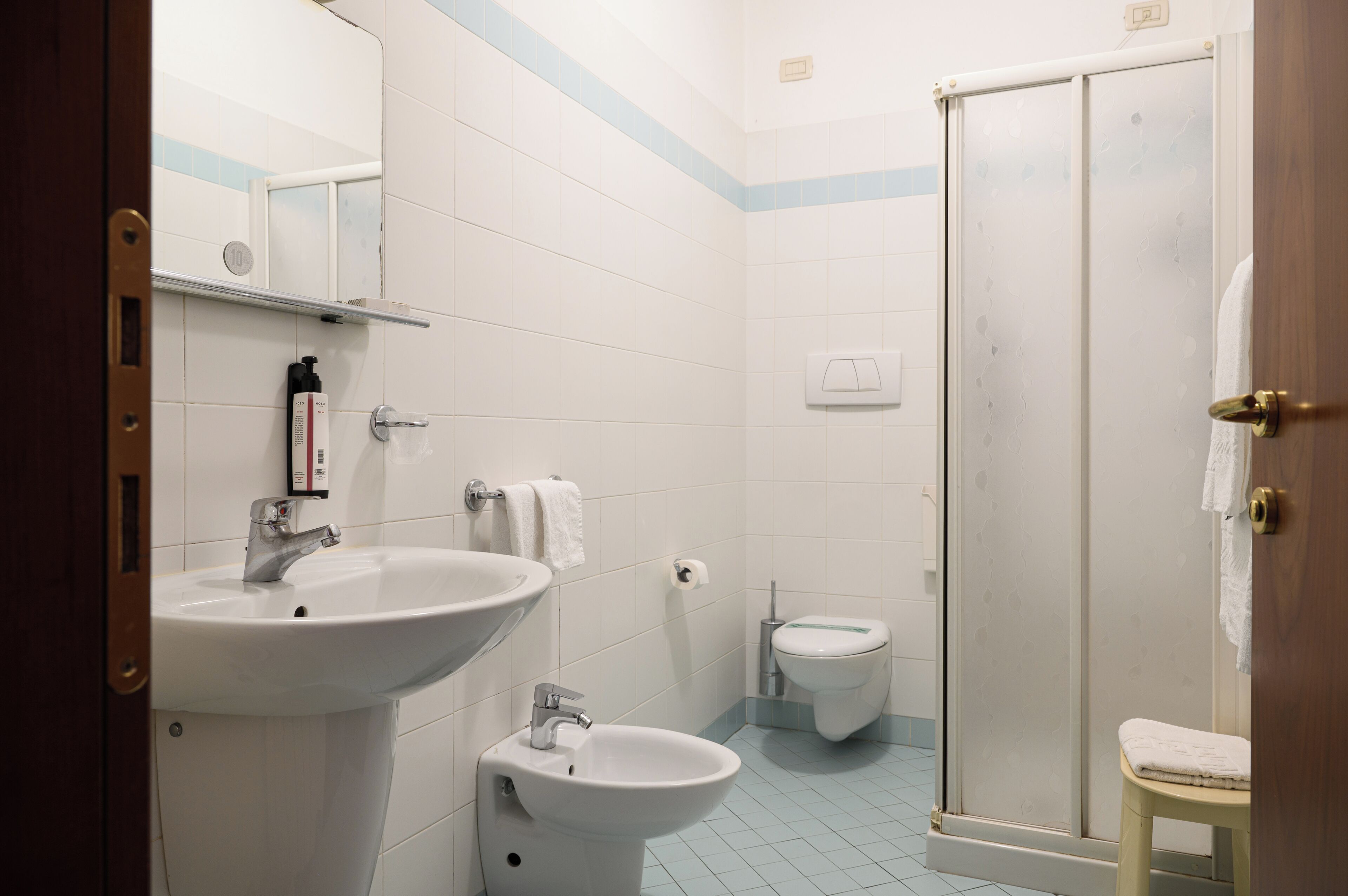 Een badkamer met een wastafel, bidet, toilet en douche.