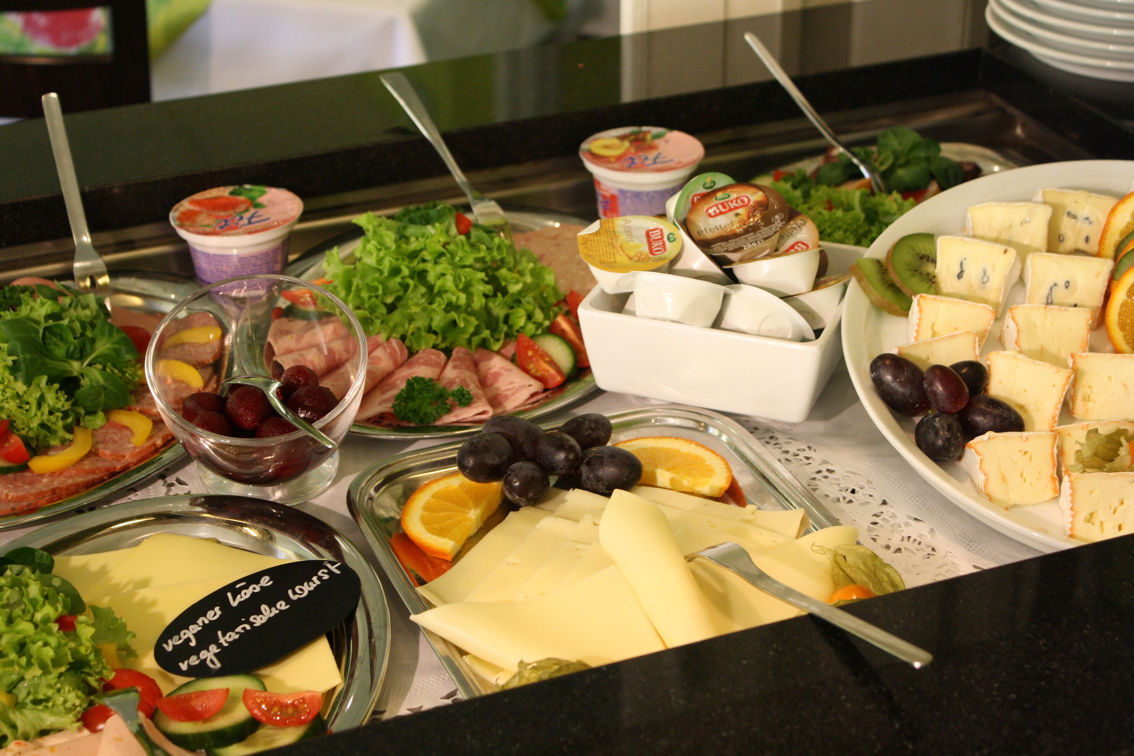 Un bufé con diversas opciones de comida, incluyendo ensaladas, quesos y frutas.