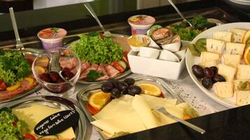 Un bufé con diversas opciones de comida, incluyendo ensaladas, quesos y frutas.