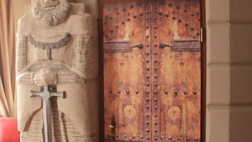 A stone statue of a figure holding a sword in front of a wooden door with metal reinforcements.
