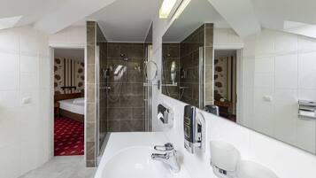 Un baño moderno con un espejo grande, una bañera y una zona de ducha.