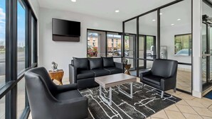 A modern lobby with a black leather sofa, a wooden coffee table, and a black armchair.
