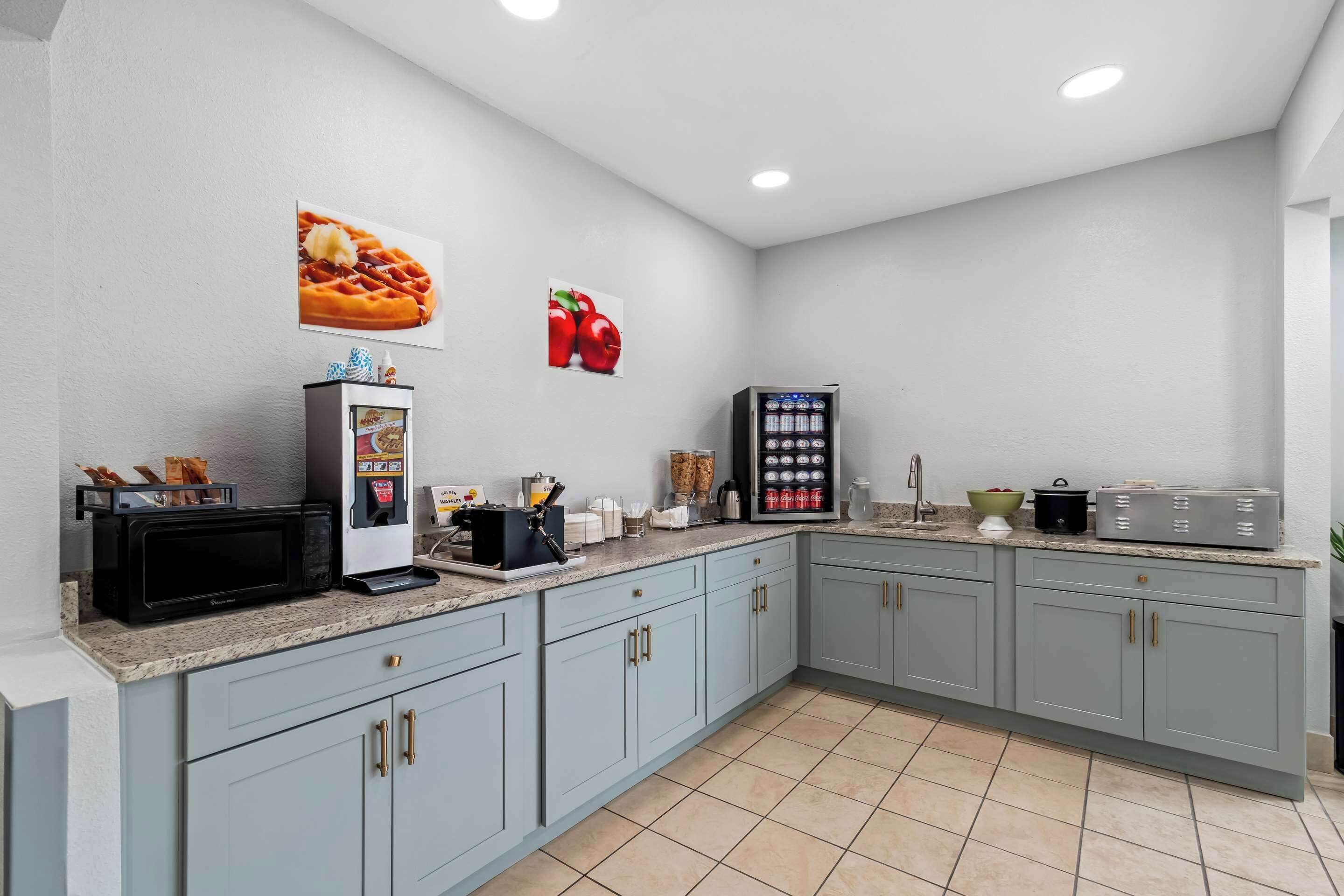 A modern kitchen with light blue cabinets, a microwave, a coffee machine, and a refrigerator.