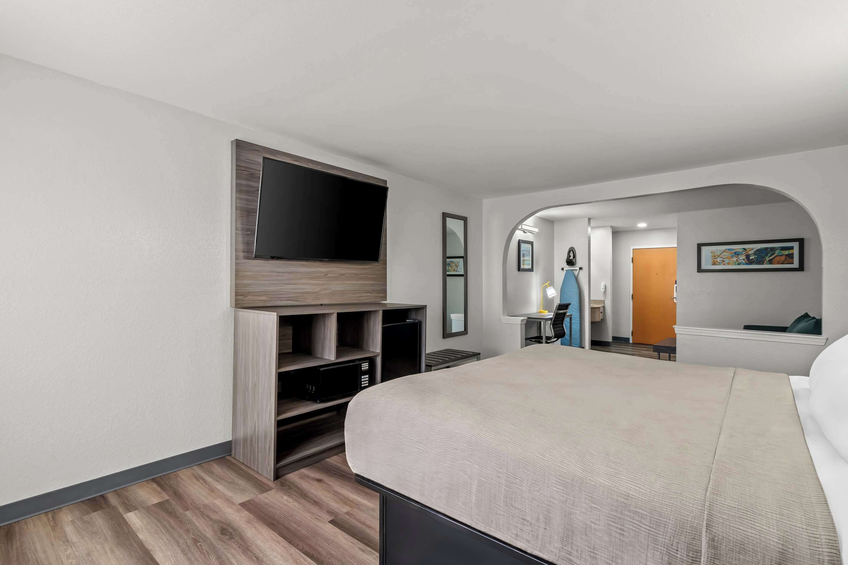A modern hotel room with a large bed, built-in TV, and a walk-in closet.