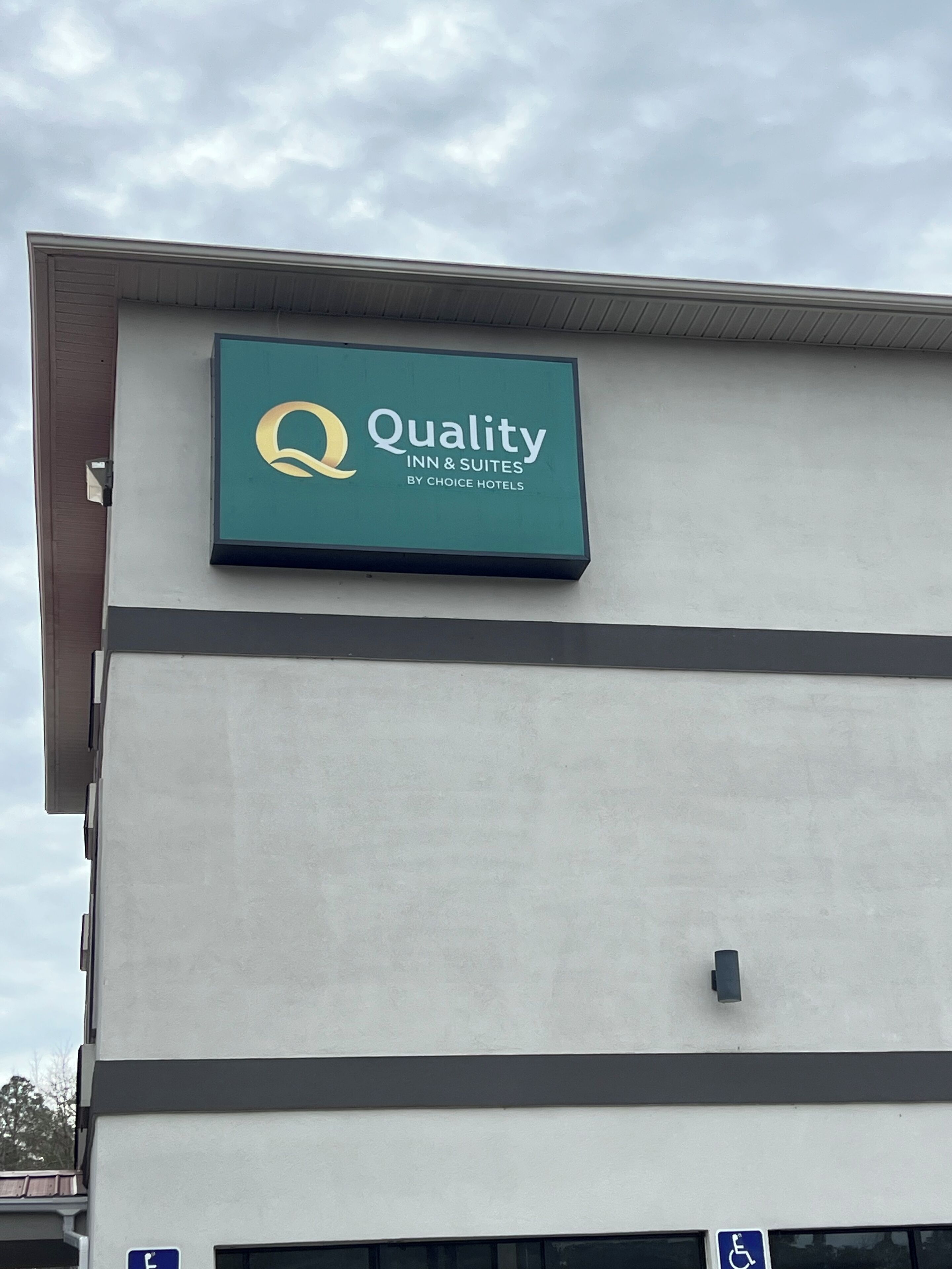 A sign for Quality Inn & Suites by Choice Hotels on a building.