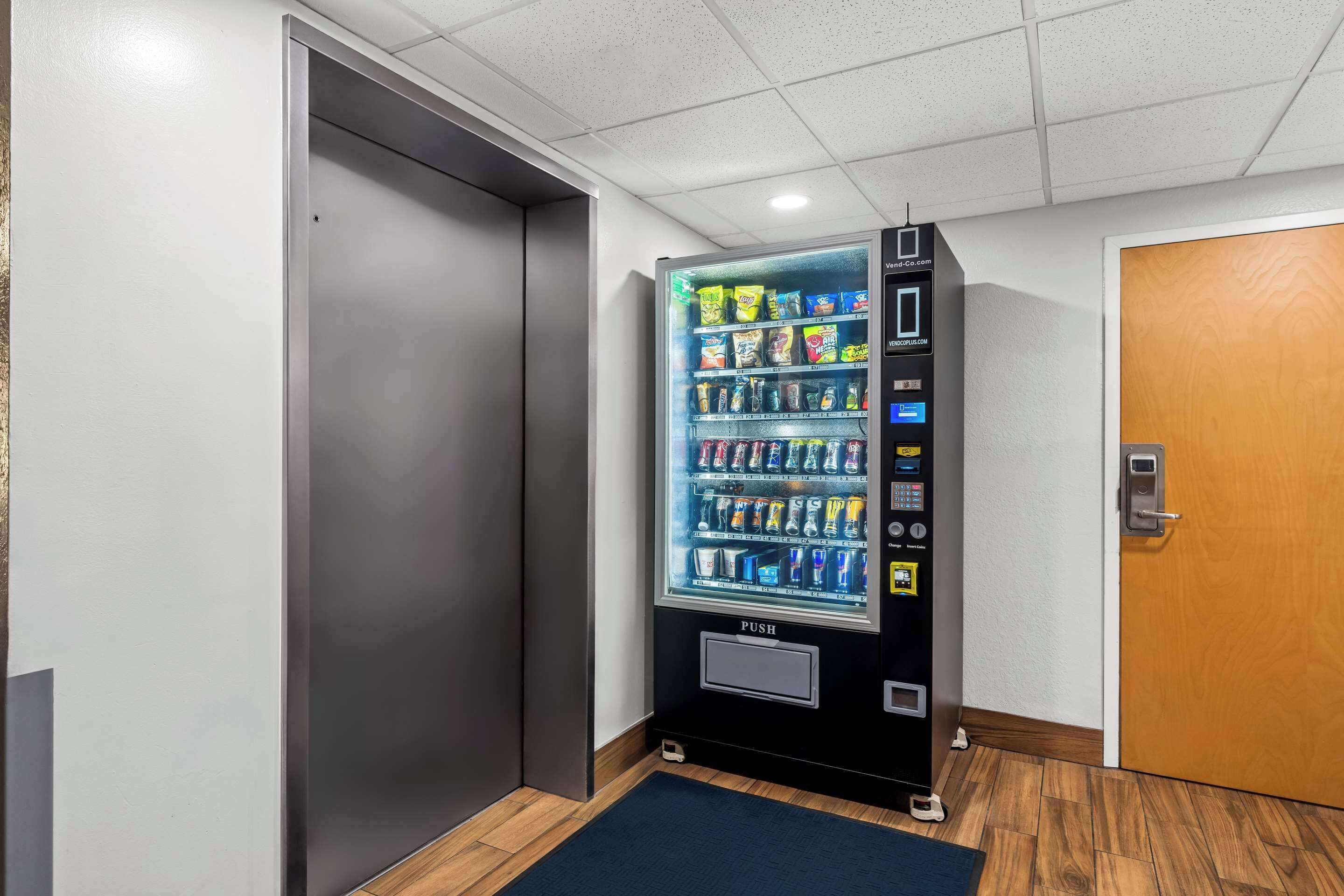 Ein Getränkeautomat mit Snacks und Getränken, eine Tür und ein Holzboden.